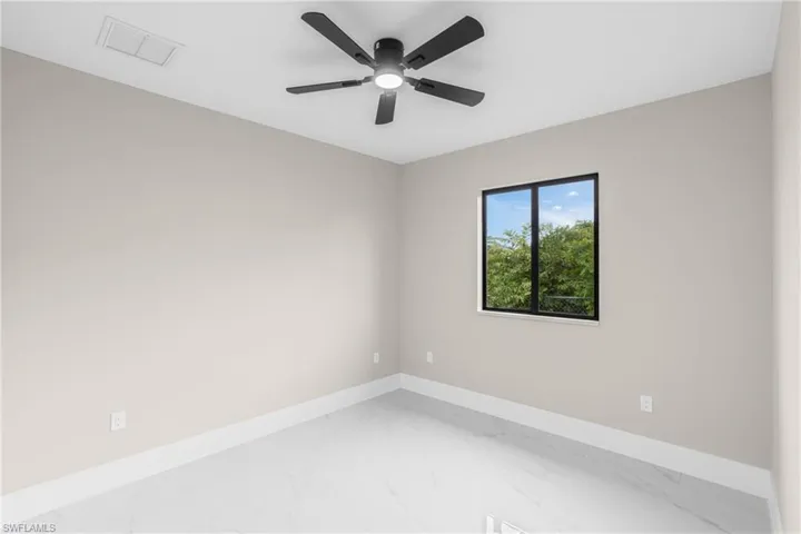Spare room featuring marble finish floors and ceiling fan