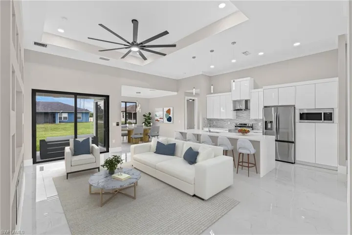 Living area with light marble finish flooring, a tray ceiling, recessed lighting, a ceiling fan, and crown molding