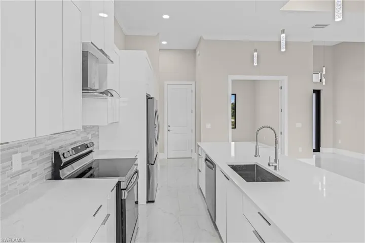 Kitchen featuring modern cabinets, appliances with stainless steel finishes, pendant lighting, white cabinetry, and crown molding
