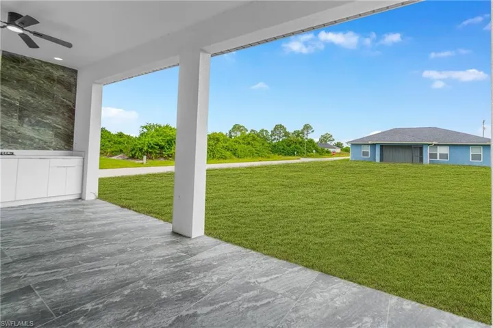 View of green lawn featuring ceiling fan and a patio area