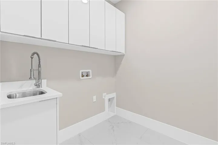 Laundry room featuring marble finish flooring, washer hookup, and cabinet space
