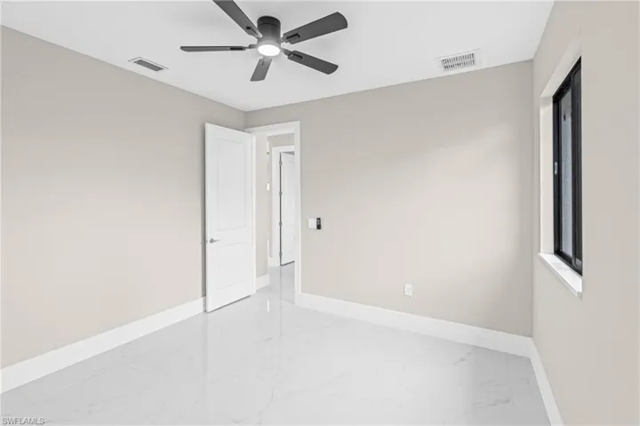 Spare room with light marble finish floors and ceiling fan