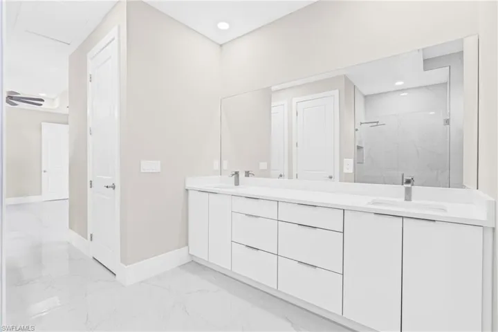 Full bath with a marble finish shower, light marble finish flooring, and double vanity