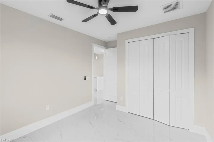 Unfurnished bedroom featuring light marble finish flooring, a closet, and a ceiling fan
