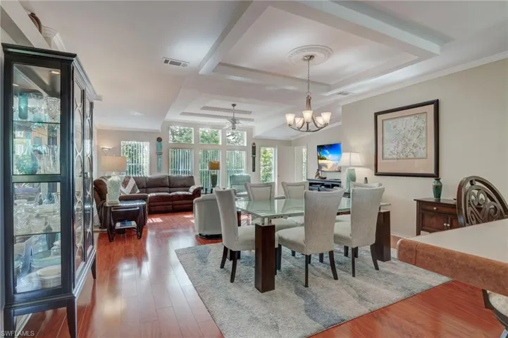 Dining room with a tray ceiling, dark hardwood / wood-style floors, and ornamental molding