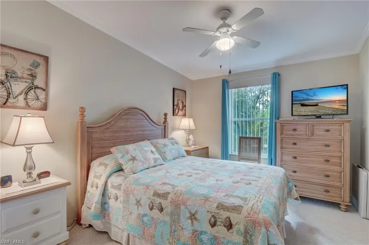 Carpeted bedroom featuring ceiling fan and ornamental molding