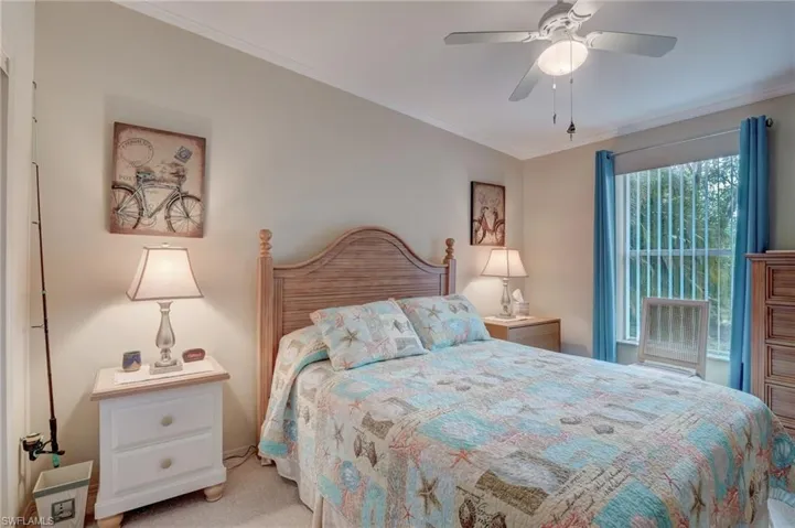 Carpeted bedroom featuring ceiling fan and ornamental molding