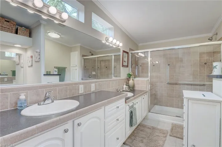 Bathroom with a shower with door, decorative backsplash, tile patterned floors, crown molding, and vanity