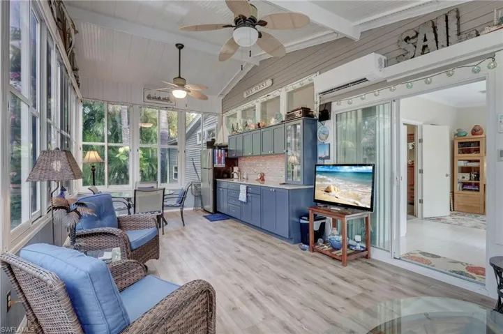 Sunroom with ceiling fan, vaulted ceiling with beams, and an AC wall unit
