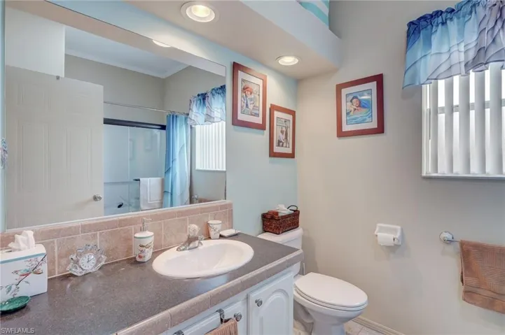 Bathroom featuring curtained shower, vanity, backsplash, toilet, and crown molding