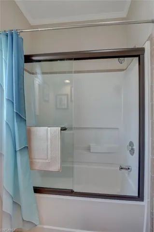 Bathroom with shower / tub combo with curtain and crown molding