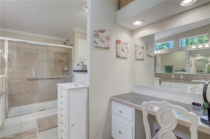 Bathroom with walk in shower, ornamental molding, vanity, and tile patterned flooring