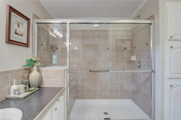 Bathroom with vanity, ornamental molding, and a shower with door