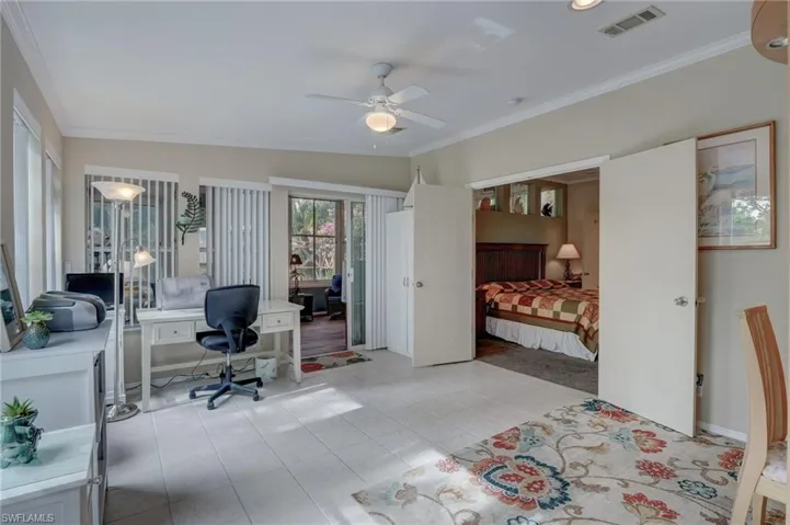 Tiled Den with ceiling fan, lofted ceiling, and ornamental molding