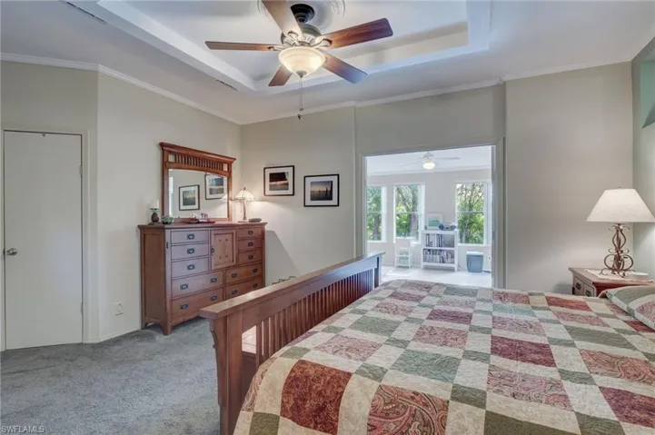 Bedroom with light carpet, ceiling fan, crown molding, and a tray ceiling