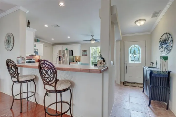 Kitchen with kitchen peninsula, appliances with stainless steel finishes, a kitchen breakfast bar, and white cabinetry