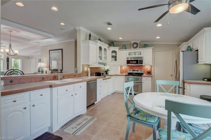 Kitchen with hanging light fixtures, white cabinets, appliances with stainless steel finishes, and sink