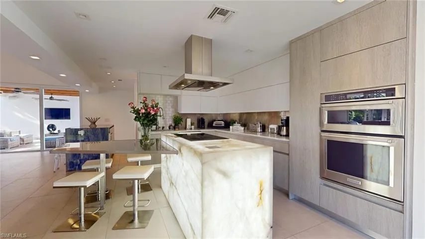 Kitchen with a kitchen breakfast bar, a center island, island exhaust hood, decorative backsplash, and stainless steel double oven