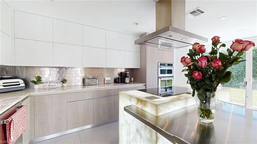 Kitchen with tasteful backsplash, island range hood, a wealth of natural light, and stainless steel double oven