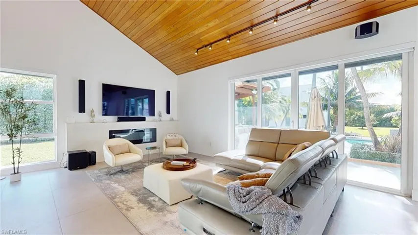 Tiled living room with plenty of natural light, rail lighting, high vaulted ceiling, and wooden ceiling