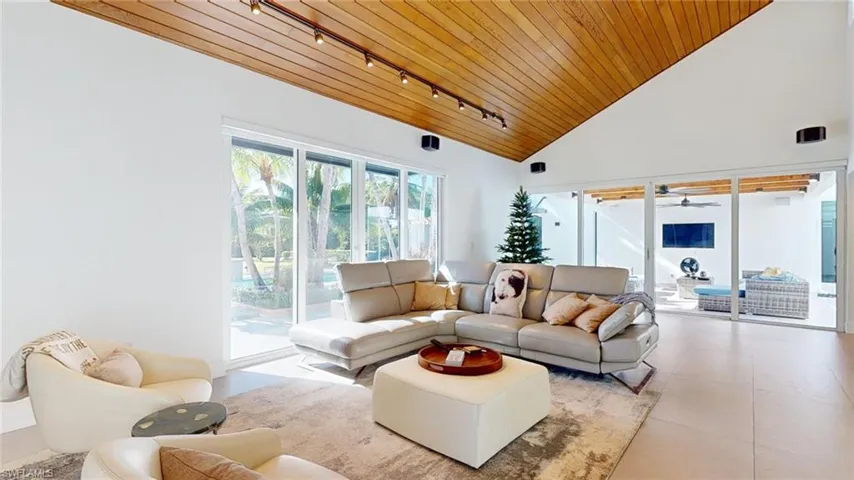 Living room featuring light tile patterned flooring, track lighting, high vaulted ceiling, and wooden ceiling
