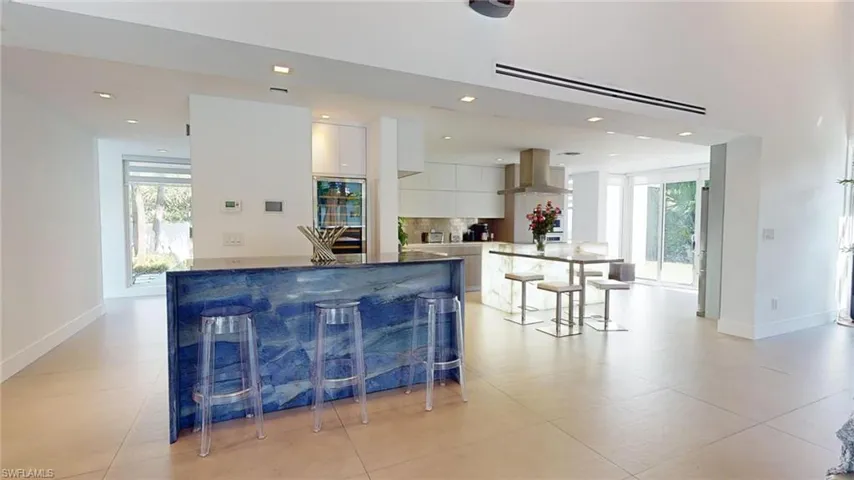 Kitchen with island range hood, a breakfast bar area, white cabinets, and plenty of natural light
