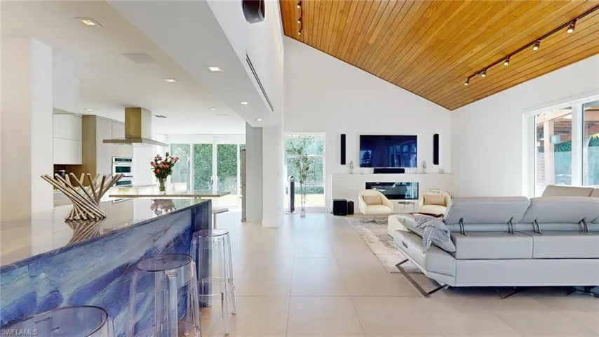 Living room featuring wood ceiling, rail lighting, high vaulted ceiling, and light tile patterned floors