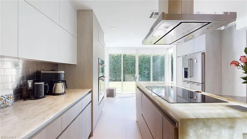 Kitchen with tasteful backsplash, stainless steel appliances, light tile patterned floors, and white cabinets
