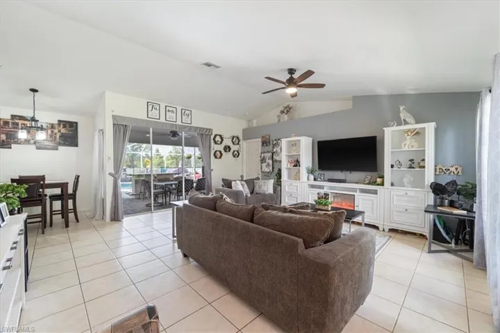 Spacious main living area featuring neutral tile flooring, a vaulted ceiling, and sliding glass doors leading to an outdoor space