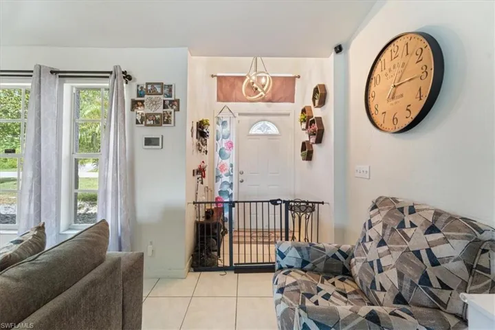 Entryway featuring a decorative pendant light fixture, white door with an arched glass insert, and tile flooring
