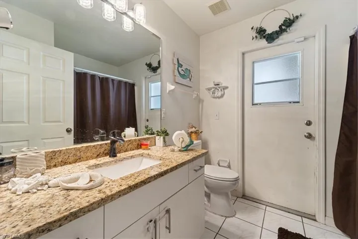 Bathroom featuring a vanity with a granite-style countertop, undermount sink, and dark-finish faucet