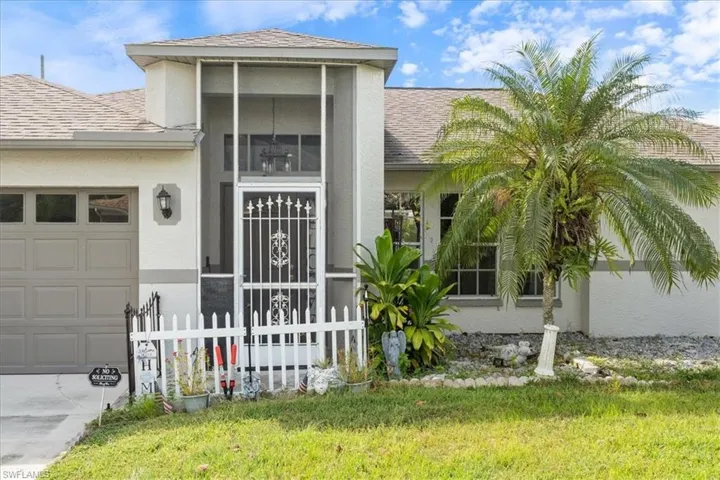 Stucco exterior with a screened entry, an integrated garage, and a traditional white picket fence