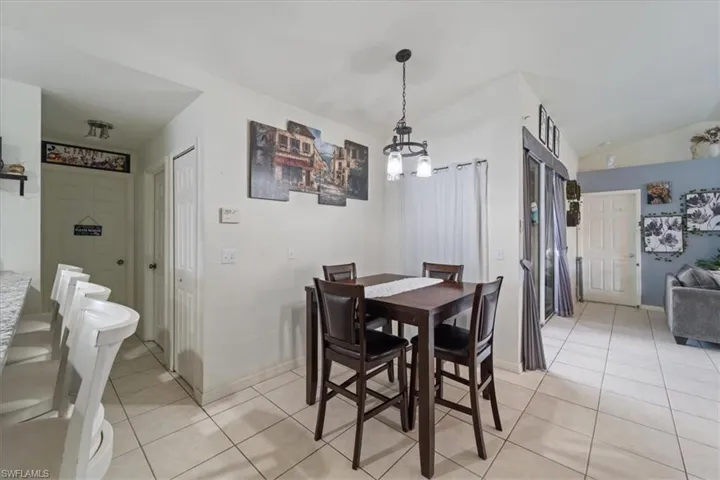 Open concept dining area with tile flooring, a contemporary pendant light fixture, and vaulted ceilings