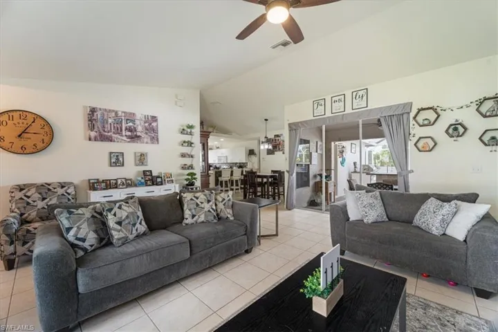 Vaulted ceilings with a ceiling fan, tile flooring, and sliding glass doors opening to the exterior