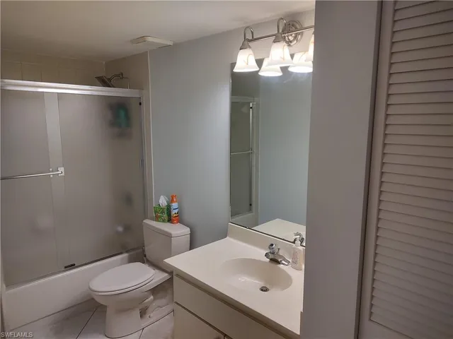 Guest bathroom with vanity, toilet, tile patterned floors, and combined bath / shower with glass door