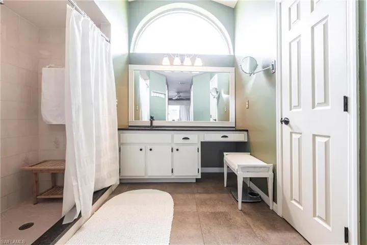 Full bath featuring a ceiling fan, tile patterned floors, a tile shower, and vanity