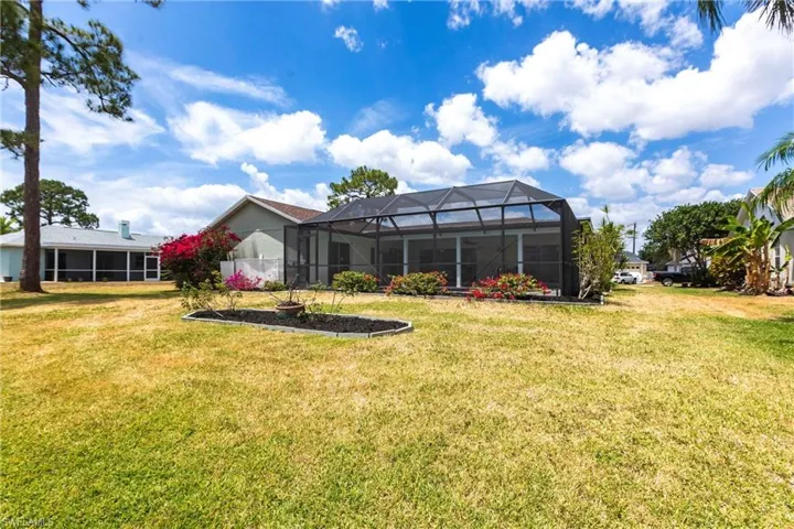 Rear view of house featuring glass enclosure and a yard