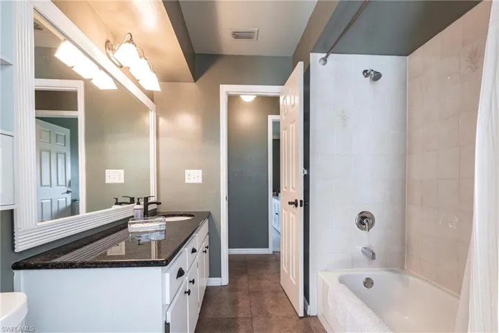 Bathroom featuring visible vents, tile patterned flooring, vanity, baseboards, and  shower combination