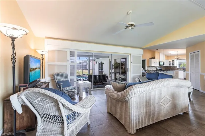 Living room with a ceiling fan, tile patterned floors, and vaulted ceiling
