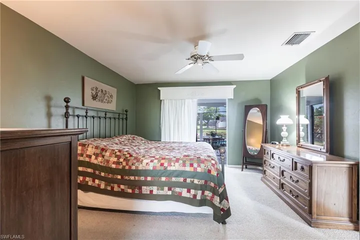 Bedroom featuring a ceiling fan, visible vents, and light carpet