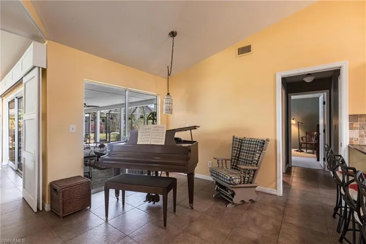 Living area with baseboards, visible vents, and lofted ceiling