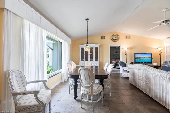Dining room with tile patterned floors, ceiling fan, lofted ceiling, and visible vents