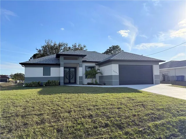 Prairie-style house with a front yard, concrete driveway, stucco siding, an attached garage, and a shingled roof