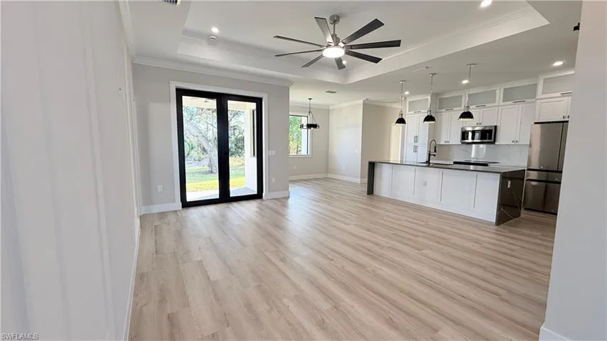 Kitchen featuring white cabinetry, stainless steel appliances, light wood-type flooring, open floor plan, and hanging light fixtures