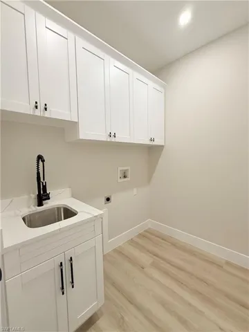 Laundry room with cabinet space, light wood-style floors, electric dryer hookup, washer hookup, and recessed lighting