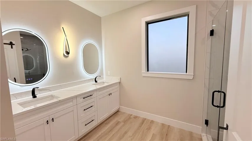 Master Bathroom featuring a stall shower, double vanity, and light wood-style floors