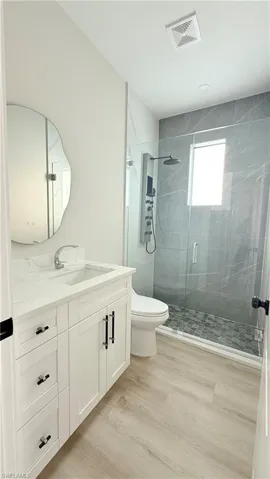 Full bath featuring a stall shower, vanity, and light wood finished floors