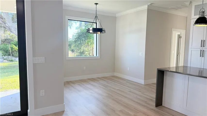 Unfurnished dining area featuring ornamental molding and light wood-style flooring