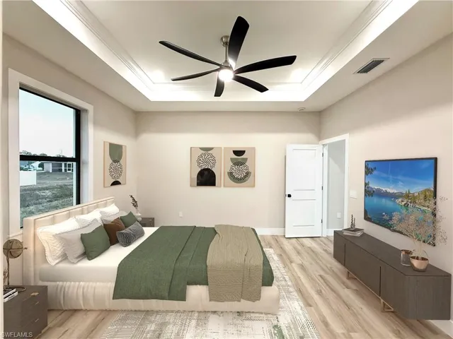 Master Bedroom featuring light wood-style flooring, a ceiling fan, ornamental molding, and a tray ceiling. Staged picture