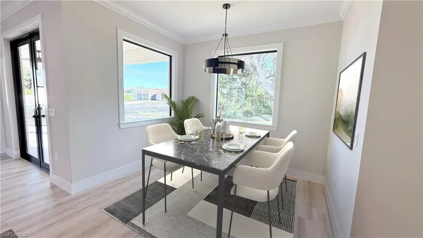 Dining area with crown molding and light wood-style floors. Staged Picture